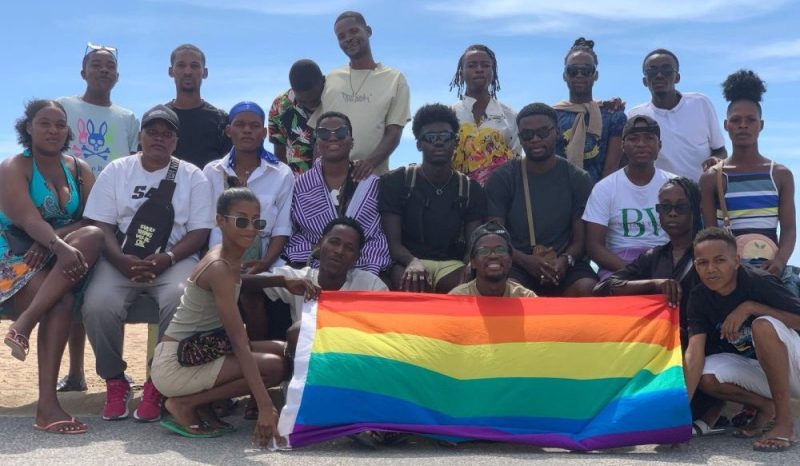 Group of people posing with a rainbow flag